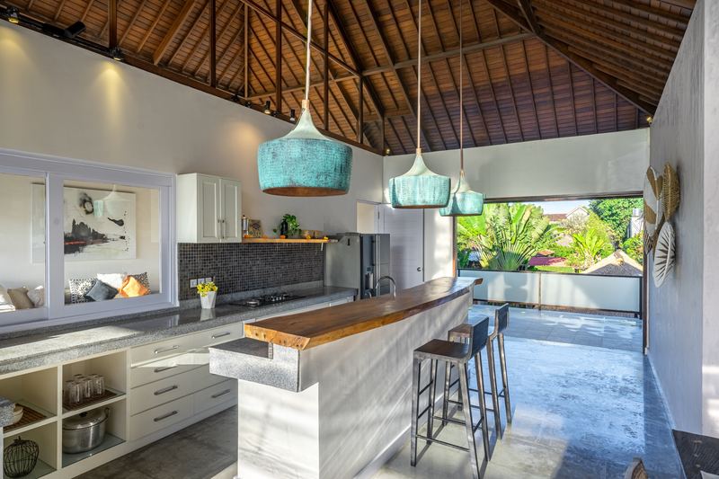 Fully equipped kitchen with marble breakfast bar, bar stools and teal pendant lights