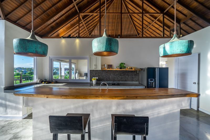 Kitchen with curved timber breakfast bar, fridge and pendant lighting