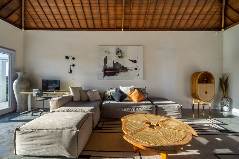 Living room with sectional sofa and round timber coffee table under a vaulted alang-alang ceiling