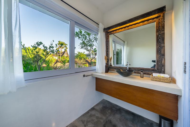 Ensuite bathroom with stone basin, carved timber mirror and garden window